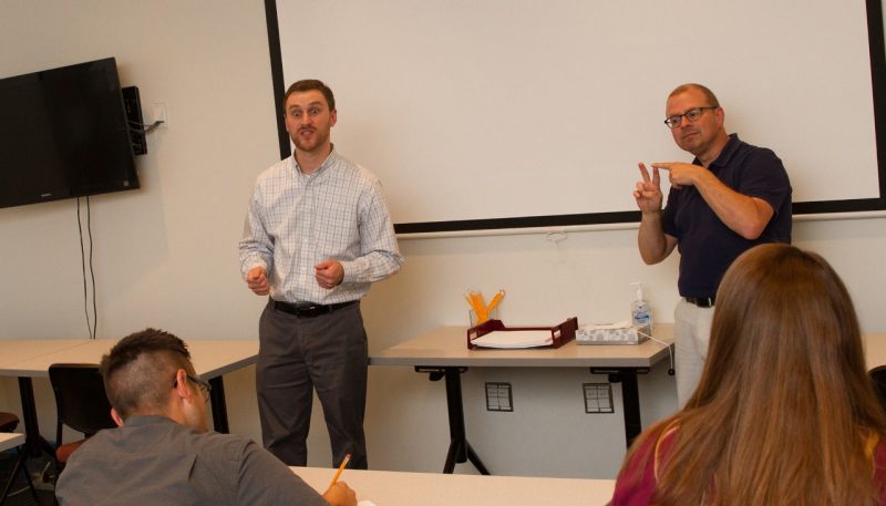 an interpreter signs at the front of a classroom